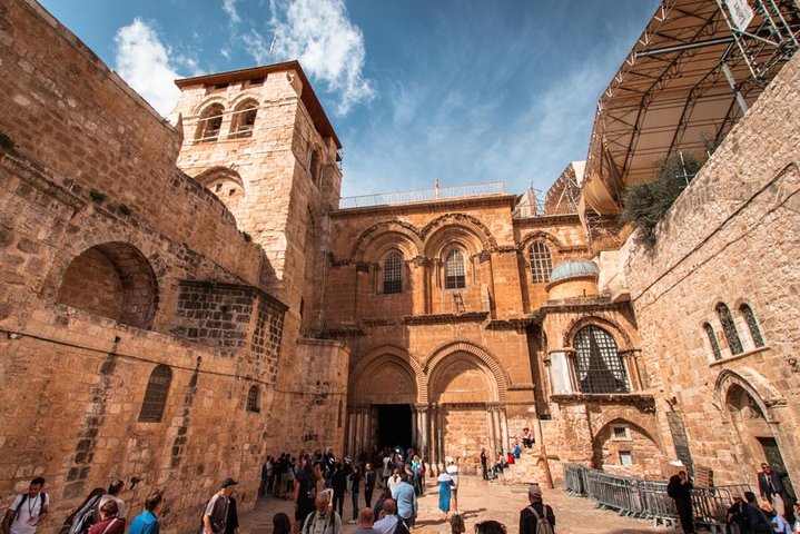 Pilgrims in modest dress walking through a stone lane in Jerusalem's Old City